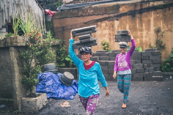 Two women balancing concrete blocks on their heads