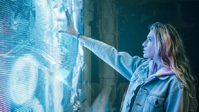 A woman reaching out to a large electronic screen