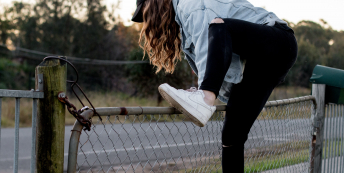 Image of woman climbing fence