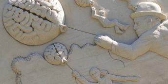 Image of sand sculpture people flying while holding brain balloons