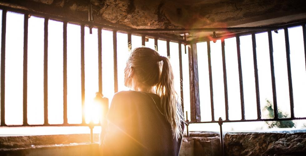 Woman behind bars of a cage