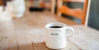 Coffee cup on a desk with the word 'Begin' on it.