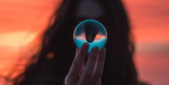Image of woman holding a glass ball at sunset