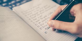 Image of person's hand writing a goal checklist