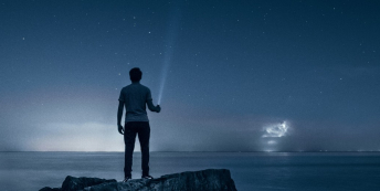 Image of a man looking out across the sea at night