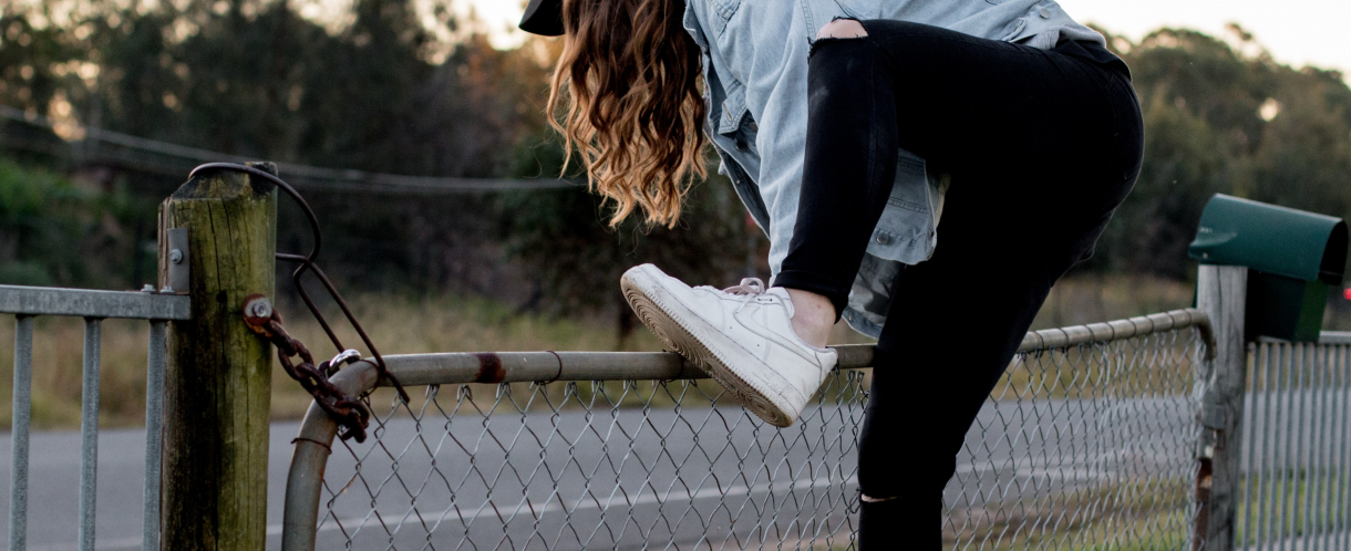 Image of woman climbing fence