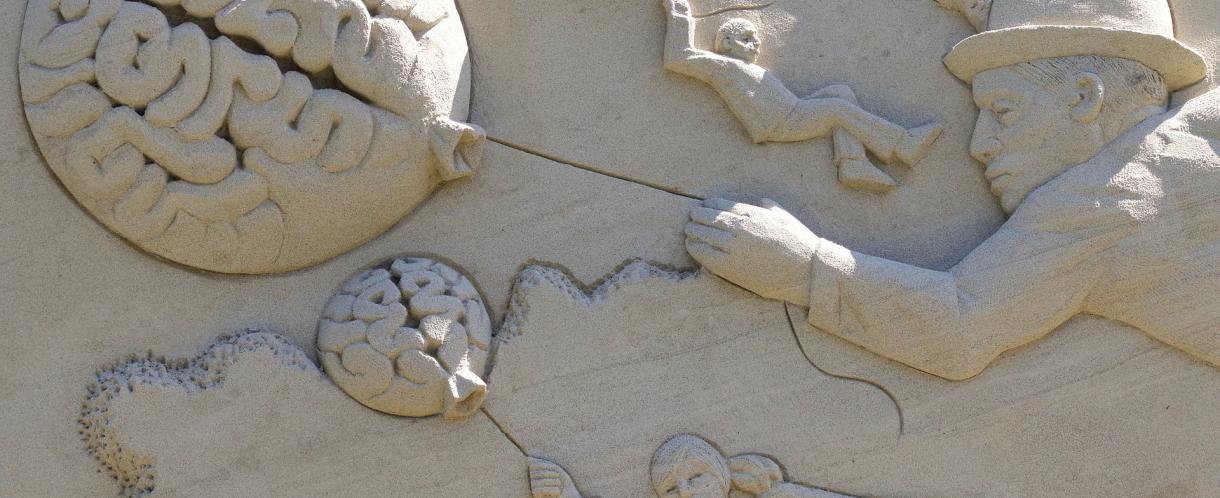 Image of sand sculpture people flying while holding brain balloons