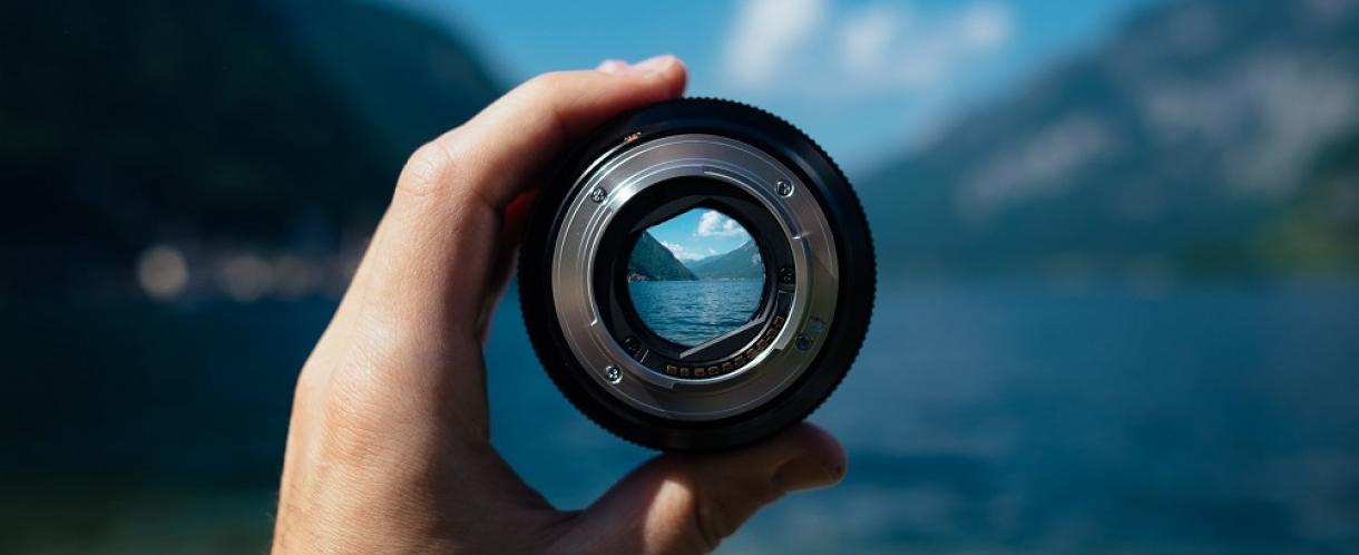 Image of camera lens held up in front of mountain view